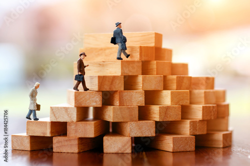 Miniature people walking on step of Wood block stack.  growth in business concept.