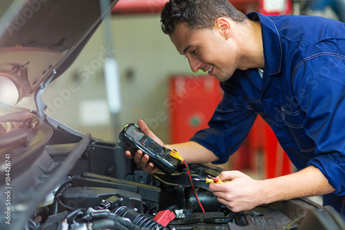 Auto mechanic checking car battery voltage
