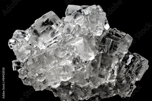 Cubic salt crystal aggregate against black background photo
