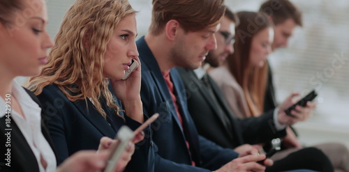 Businesspeople Using Technology In Busy Lobby Area Of Office