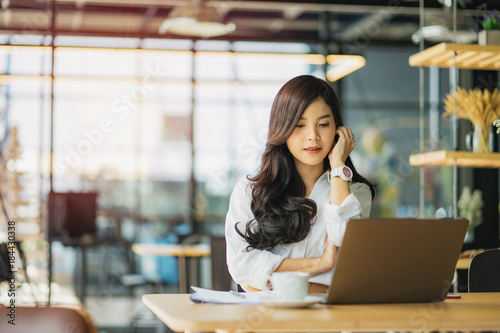 Beautiful happy young curly woman sitting in cafe and using laptop