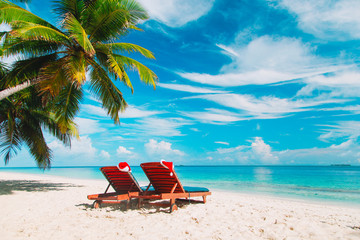 Christmas on beach -chair lounges with Santa hats at sea