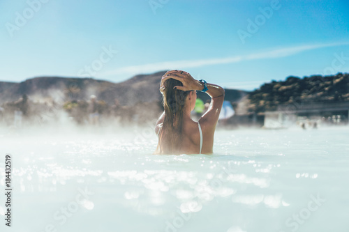 back view of young woman relaxing in hot pool in Iceland