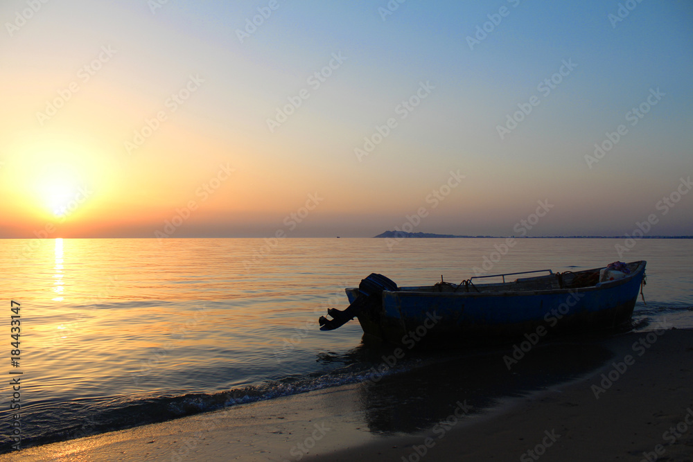 Colorful sunset at Durres, Albania, fishing boat on the beach