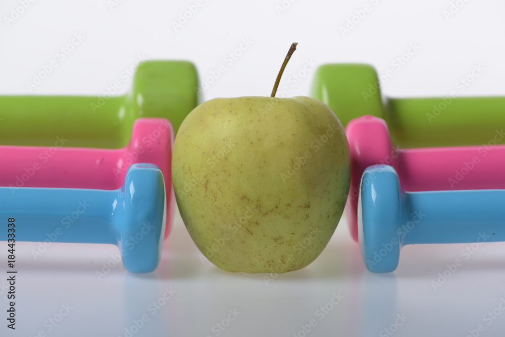 Apple fruit between pink, blue and green barbells in pattern Apple fruit between pink, blue and green barbells in pattern
