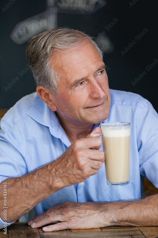 Senior thoughtful man looking away while holding cold coffee Senior thoughtful man looking away while holding cold coffee