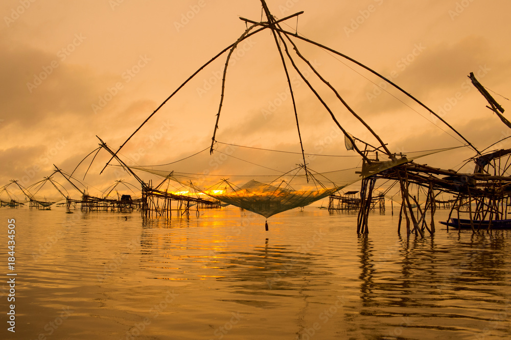 Beautiful landscape view sunrise at Pak Pra lake, Pattalung, Thailand with twilight sky background,silhouette of traditional fishing method using a bamboo square dip net.