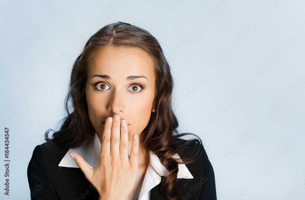 Business woman covering mouth, over blue Business woman covering mouth, over blue