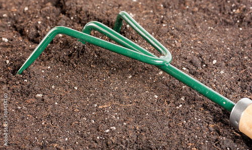 Small gardening fork in black composted soil © Emoji Smileys People
