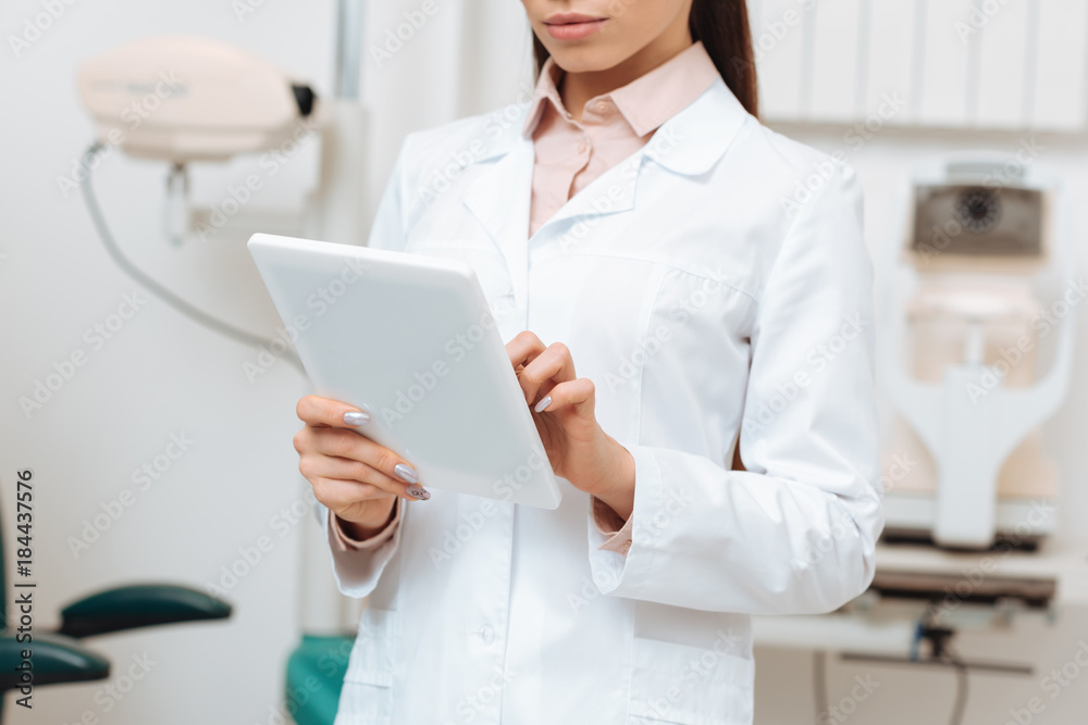 cropped shot of optometrist using digital tablet in hands in clinic