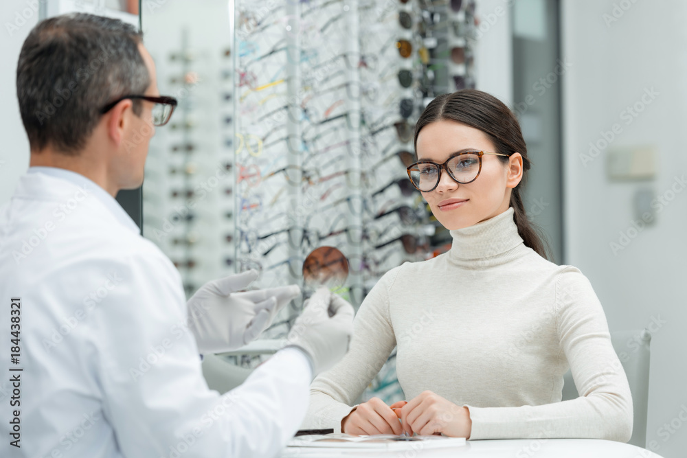 Obraz premium partial view of optometrist showing lens to patient in optics