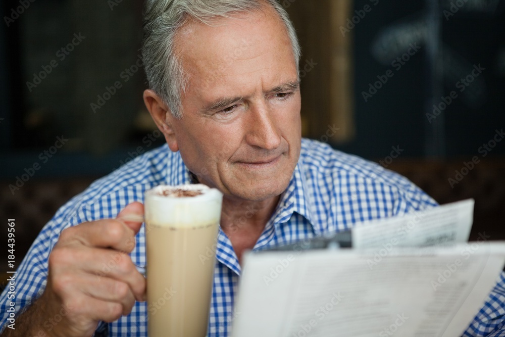 Senior man reading newspaper while sitting at cafe Senior man reading newspaper while sitting at cafe