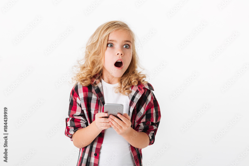Portrait of a shocked little girl holding mobile phone Portrait of a shocked little girl holding mobile phone