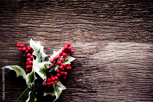 Holly berry leaves Christmas decoration on old wooden background, vintage tone. Holiday Concept