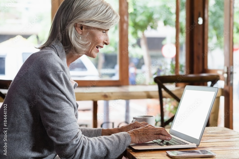 Side view of senior woman using laptop computer while sitting at