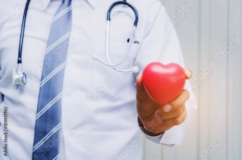 pharmacist or doctor with stethoscope around his neck and hand holding red heart in hospital, heart attack, pharmacy, laboratory research, science, chemical, health care and medical technology concept
