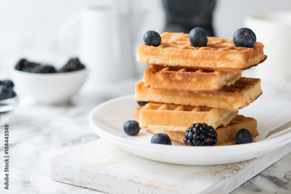 Waffles on a white plate decorated with blueberries with marbled background. copy space Waffles on a white plate decorated with blueberries with marbled background. copy space