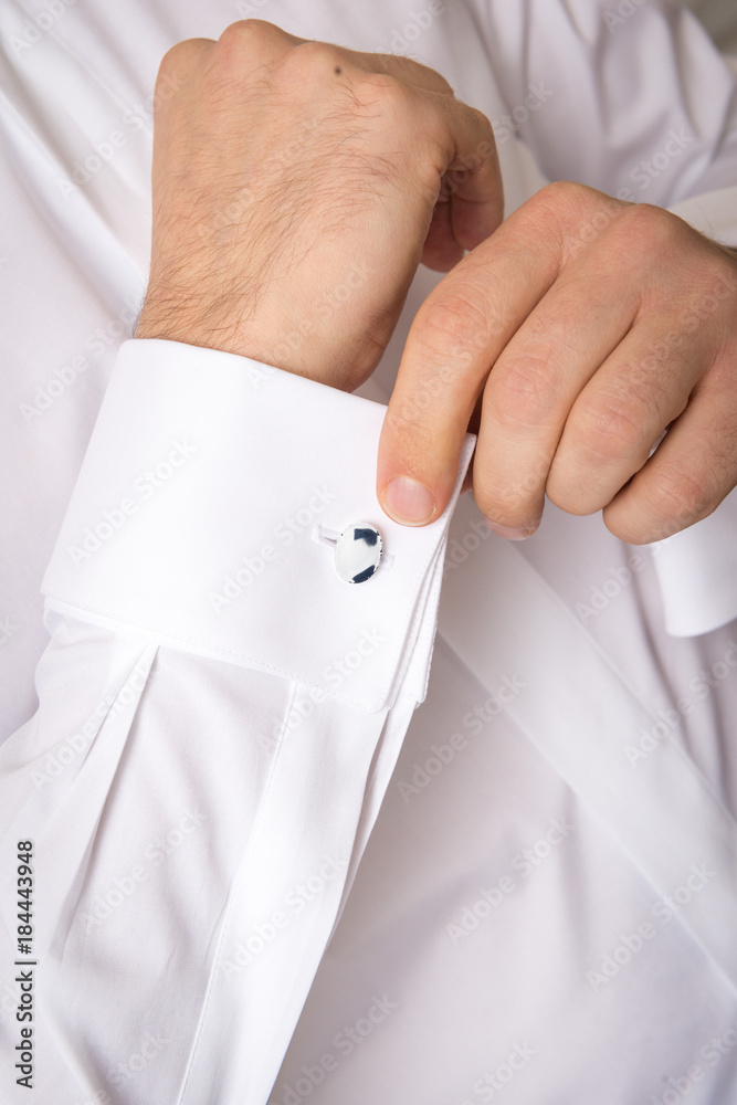 Mani maschili che sistemano la piegatura del polsino doppio con gemelli  della camicia bianca indossata Stock Photo | Adobe Stock