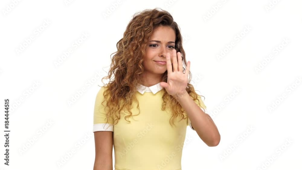 Pretty curly brunette woman in dress hinting at a wedding and pointing at her finger over white background Pretty curly brunette woman in dress hinting at a wedding and pointing at her finger over white background