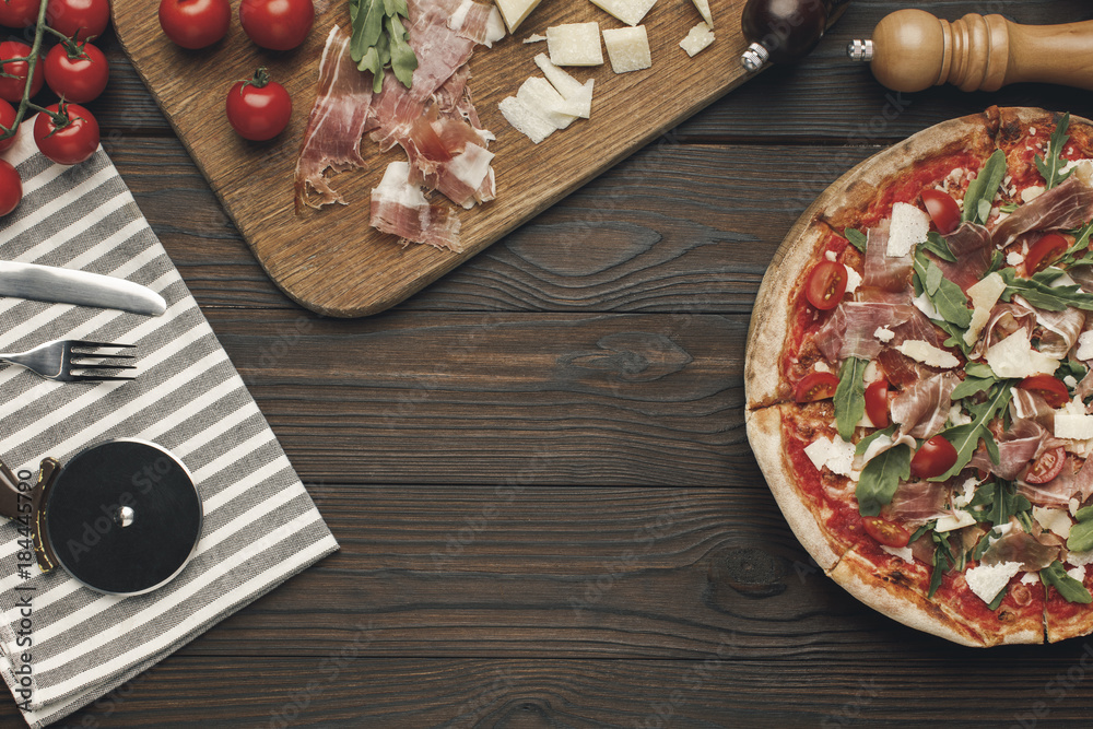 flat lay with arranged italian pizza, cutlery and various ingredients on wooden surface flat lay with arranged italian pizza, cutlery and various ingredients on wooden surface