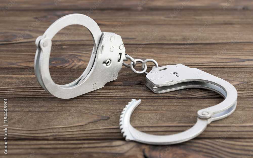 iron handcuffs on the background of a wooden table iron handcuffs on the background of a wooden table