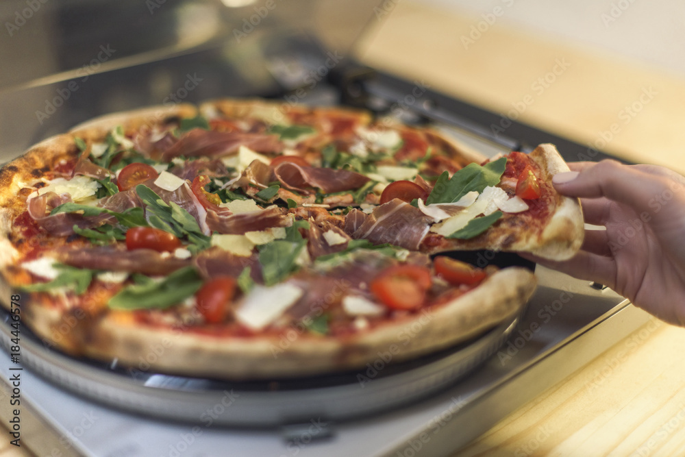 partial view of woman taking piece of italian pizza on vinyl record player partial view of woman taking piece of italian pizza on vinyl record player
