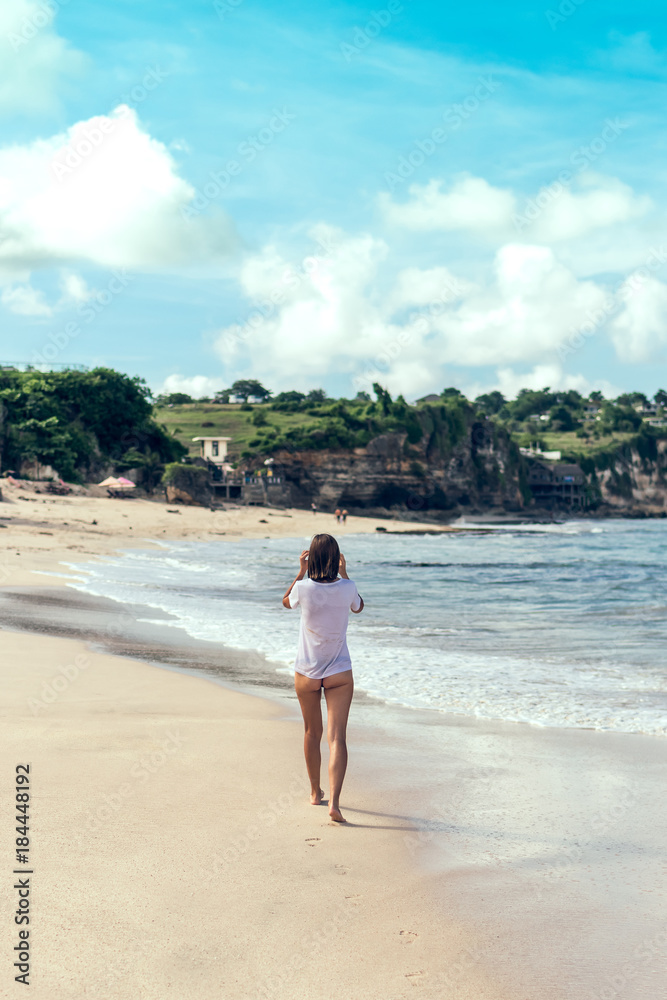 Beautiful young woman in bikini posing on the beach of a tropical island of Bali, Indonesia.