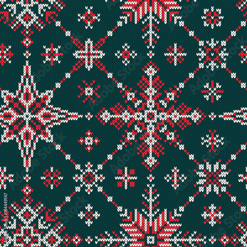 Seamless knitted pattern with red and white snowflakes on a green background