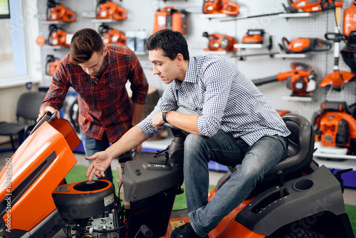 A consultant in a garden tools store shows a customer a lawn mower.