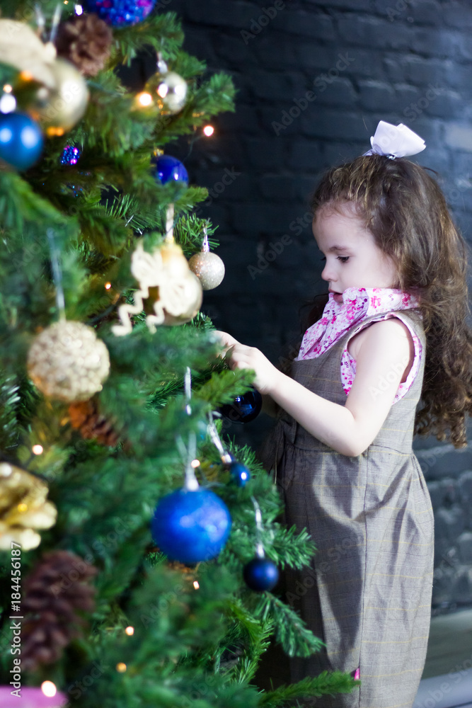 Little kid girl decorating christmas tree for new year celebration.