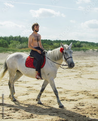 Man necked on the white horse on the beach