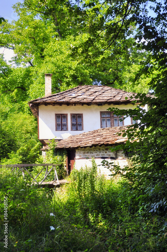 Traditional Bulgarian house in the countryside. Green surrounding © miladrumeva