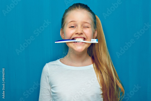 Little girl holding toothy brush with teeth.
