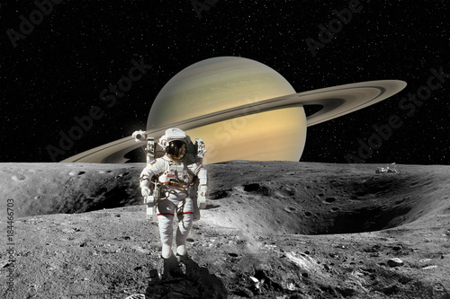 Fototapeta Naklejka Na Ścianę i Meble -  Astronaut on Planet Saturn from Saturn moon surface. Elements of this image furnished by NASA