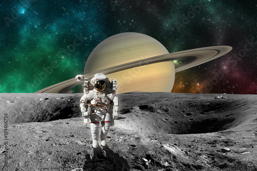 Fototapeta Naklejka Na Ścianę i Meble -  Astronaut on Planet Saturn from Saturn moon surface. Elements of this image furnished by NASA
