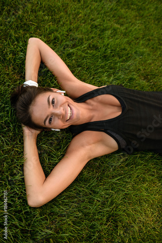 Top view of a happy fitness girl in earphones laying