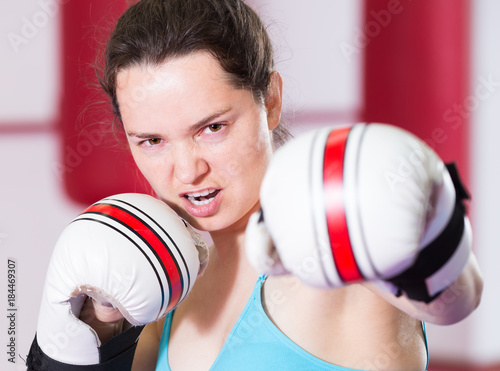 Emotional sportwoman in the boxing hall practicing boxing punches © JackF