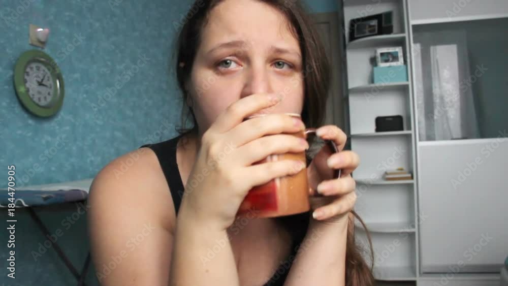 Woman desperate at home. Victim of Abuse Violence. Caucasian girl with long brown hair crying in her room with blue and white. Fat body with overweight. Postpartum Depression.girl drinks from a cup Woman desperate at home. Victim of Abuse Violence. Caucasian girl with long brown hair crying in her room with blue and white. Fat body with overweight. Postpartum Depression.girl drinks from a cup