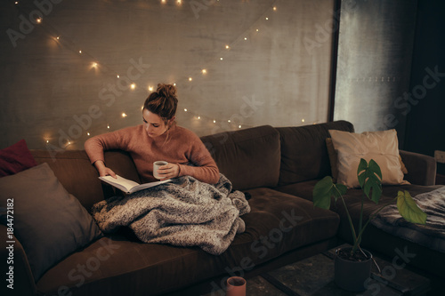 Woman reading book in cozy living room