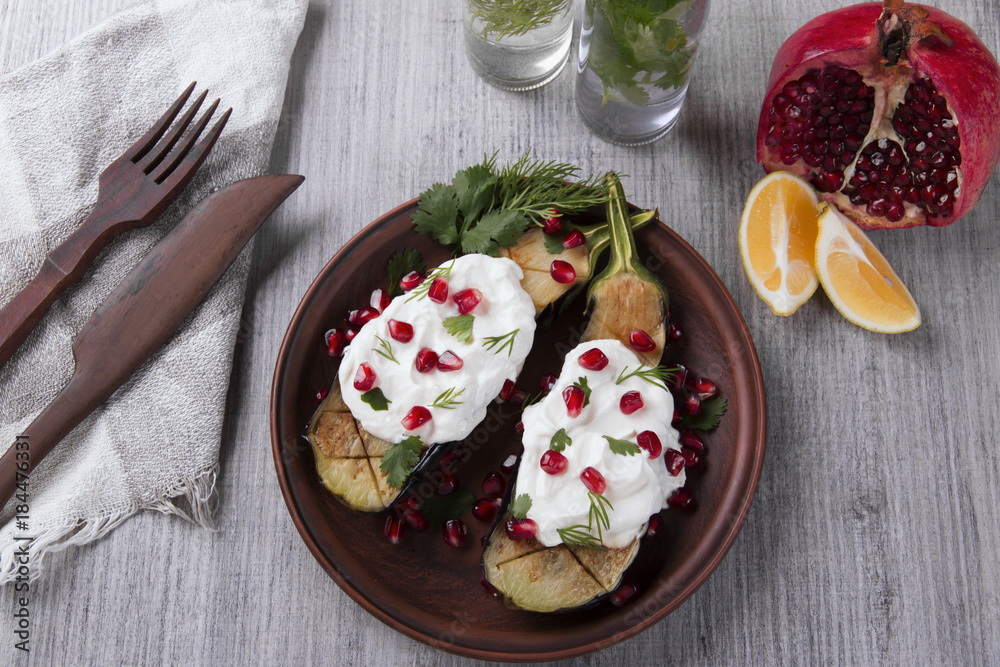 baked eggplants on a plate with cream cheese and pomegranate seeds