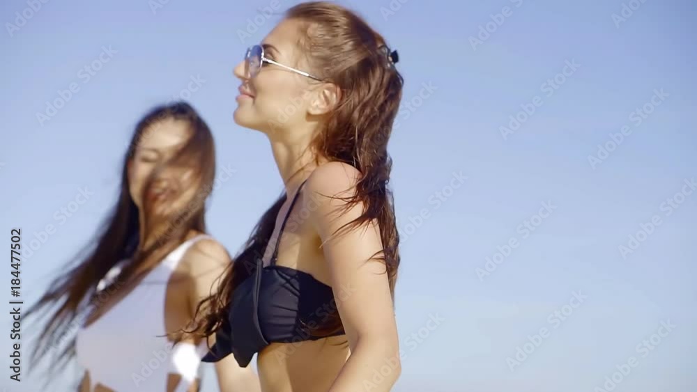 cheerful girlfriends in stylish swimsuits stroll on the beach, the ladies flirt with each other cheerful girlfriends in stylish swimsuits stroll on the beach, the ladies flirt with each other