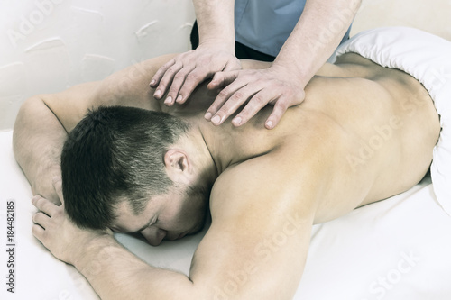 The process of health-improving sports massage is done by a man in a medical clinic photo
