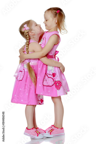 Two little girls hug.