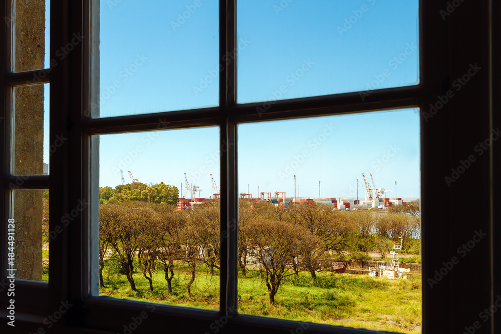 Port with containers and cranes seen through a window Port with containers and cranes seen through a window
