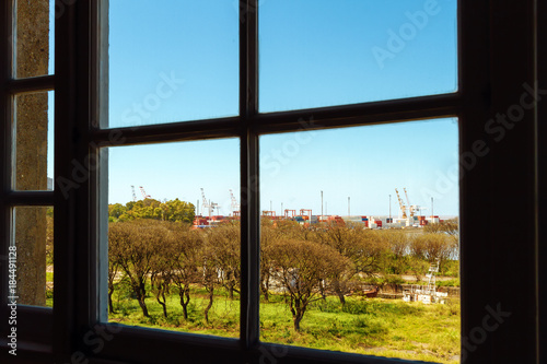Port with containers and cranes seen through a window
