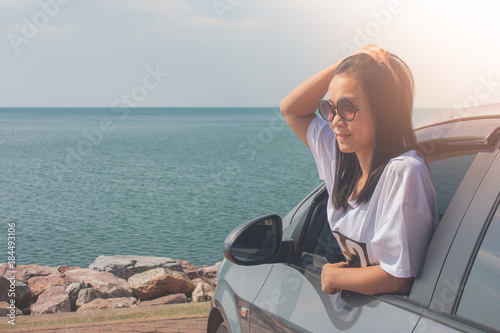 Vacation and Holiday Concept : Happy family car trip at the sea, Portrait woman wearing sunglasses and feeling happiness in silver car.