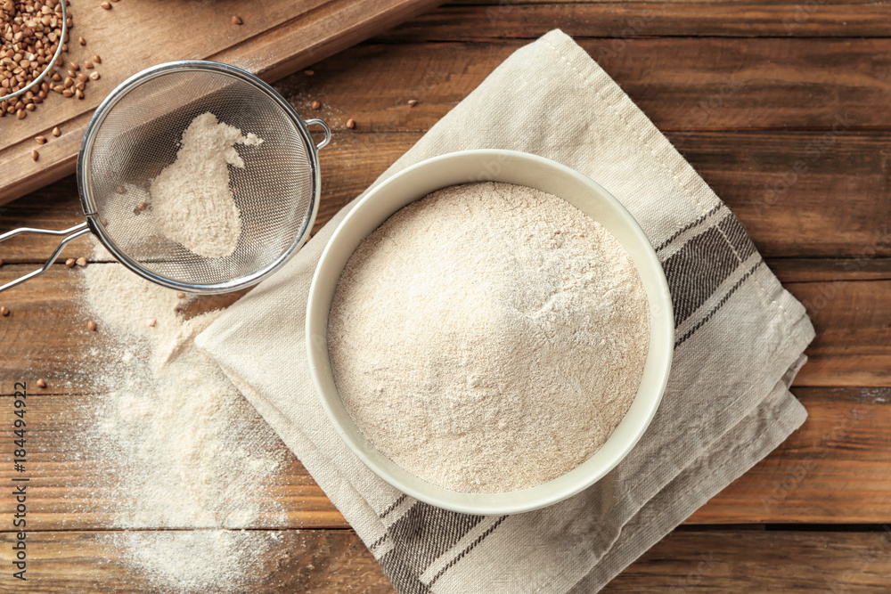 Ceramic bowl and sieve with buckwheat flour on table Ceramic bowl and sieve with buckwheat flour on table
