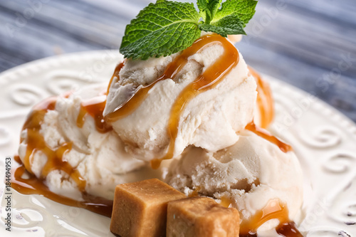 Obraz na plátně Delicious ice cream with caramel topping on plate, closeup