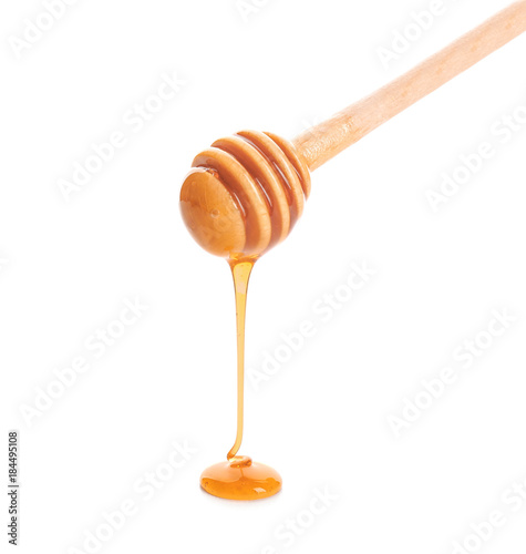 Honey dripping from dipper on white background