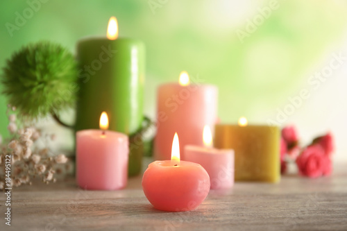 Wax candles burning on table against blurred background, closeup
